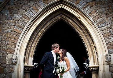 wedding kiss under the arch of a church